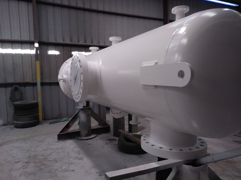 A primed horizontal separator vessel on stands inside the fabrication shop